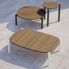 three wooden tables sitting next to each other on top of a cement ground with white metal legs