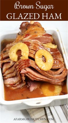 brown sugar glazed ham in a white dish with pineapples on the side and text overlay