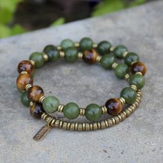 Jade and Tigers Eye Mala Bracelet. Made with genuine jade and tigers eye. Brass hand made beads support women in Africa. Contains 27 beads so its a wrist mala! Stringed on our signature and exclusive thick hitec elastic. Made in the USA. Jade is said to bring harmony to the wearer and to attract prosperity and abundance. Tiger's Eye is a stone of protection. It enhances integrity, willpower, practicality and correct use of power.