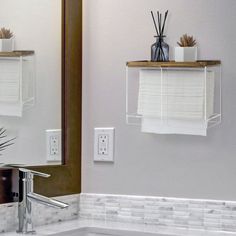 a bathroom with a sink, mirror and shelf above the toilet paper roll holder on the wall