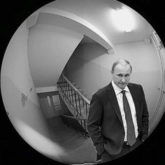 a man wearing a suit and tie standing in front of a staircase