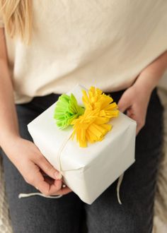 a woman holding a white present box with yellow flowers