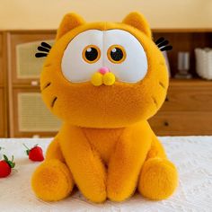 a yellow stuffed cat sitting on top of a bed next to strawberries and milk