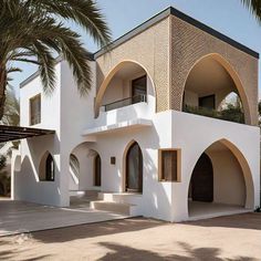 a large white building with arched windows and doors on the outside, surrounded by palm trees