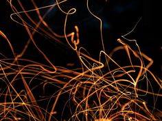 an abstract photograph of orange and yellow lines on a black background in the night time