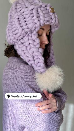 a woman wearing a purple hat with white fur pom - pom on it