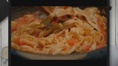 a pan filled with pasta being stirred by a ladle