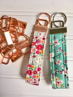 three different types of key chains on a white surface with flowers and leaves in them