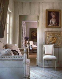 a bedroom with white furniture and paintings on the wall