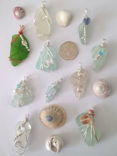 a collection of sea glass and seashells on a white surface with a green leaf