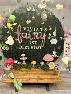 a birthday party backdrop with balloons and flowers on the table in front of it is a sign that says, vivan's fairy 1st birthday