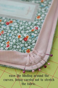 a close up of a piece of fabric on top of a cutting board with the words, ease the binding around the curves, being careful not to stretch the fabric