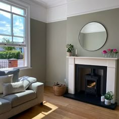 a living room with a couch, mirror and fire place in the middle of it