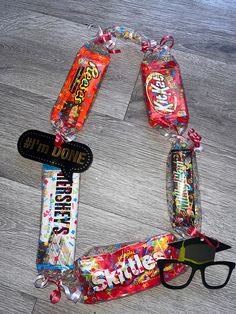 a pair of glasses sitting on top of a wooden floor next to candy bar wrappers