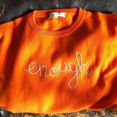 an orange sweater with the word enough written on it