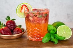 a drink with strawberries and limes next to it