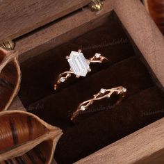 two rings in a wooden box with leaves on the bottom and an open ring inside