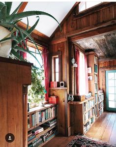 a living room filled with lots of books on top of a wooden floor next to a window