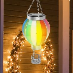 a multicolored lantern hanging from a chain on the front porch with christmas lights around it