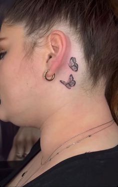 a woman with tattoos on her neck and behind the ear is a small butterfly tattoo