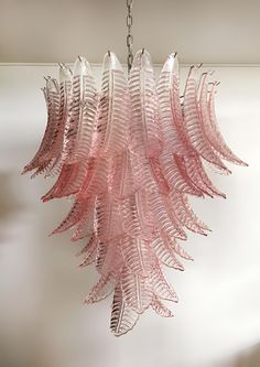 a pink glass chandelier hanging from a ceiling in a room with white walls