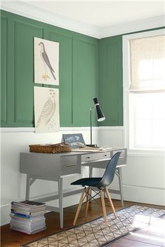 an office with blue walls and white trim on the walls, along with a gray desk