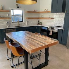 a large wooden table sitting in the middle of a kitchen next to a stove top oven