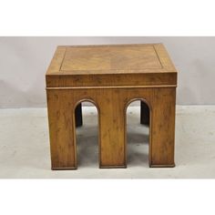 a small wooden table with two arches on the top and one at the bottom, against a white background