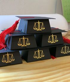 four black boxes with gold scales on them and red tassels around the edges