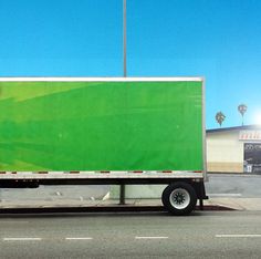 a large green truck is parked on the side of the road