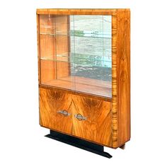 a wooden display case with glass doors on the top and bottom shelf, in front of a body of water