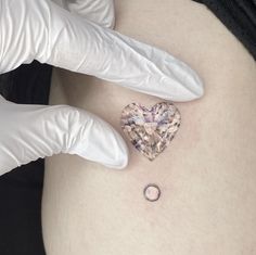 a pregnant woman's stomach with a small heart tattoo on her belly and white gloves