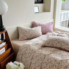 a bed sitting next to a window in a room with white flowers on top of it