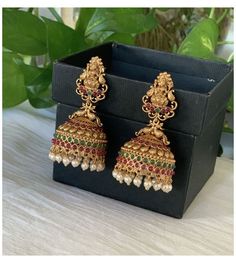 a pair of gold toned earrings with multicolored stones and pearls hanging from them