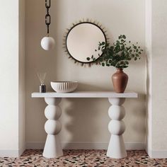 a white table with a mirror and vase on it