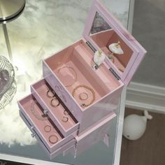 an open pink jewelry box sitting on top of a table