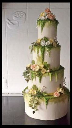 a three tiered cake with flowers and greenery on it