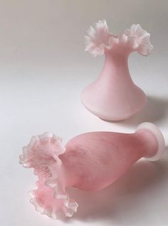 two pink vases sitting next to each other on a white surface