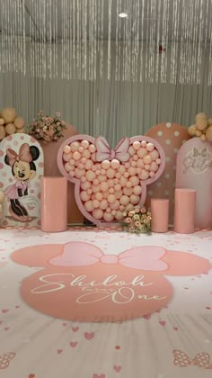 a table topped with lots of pink and white candies next to mickey mouse decorations