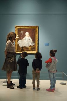 three children looking at an old painting in a museum with two adults and one child