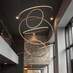 a large circular chandelier hanging from the ceiling in an office building with brick walls