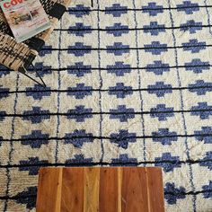 a wooden table sitting on top of a blue and white rug next to a magazine