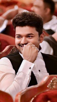 a man sitting in a chair with his chin resting on his hand and smiling at the camera