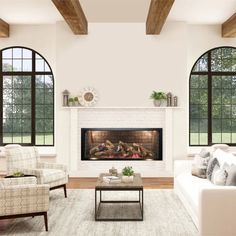 a living room with couches, chairs and a fire place in front of two large windows