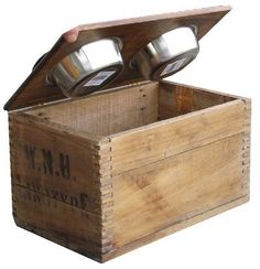 an old wooden box with two metal cups in it