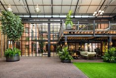 the inside of a building with lots of plants and potted plants in front of it