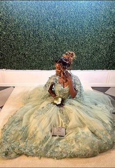 a woman in a green dress sitting on the floor next to a wall with plants