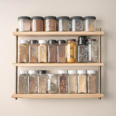 an assortment of spices on wooden shelves in a kitchen