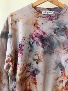 a tie dye t - shirt hanging on a wooden hanger