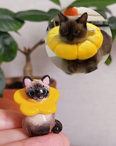 a cat figurine sitting on top of a yellow object